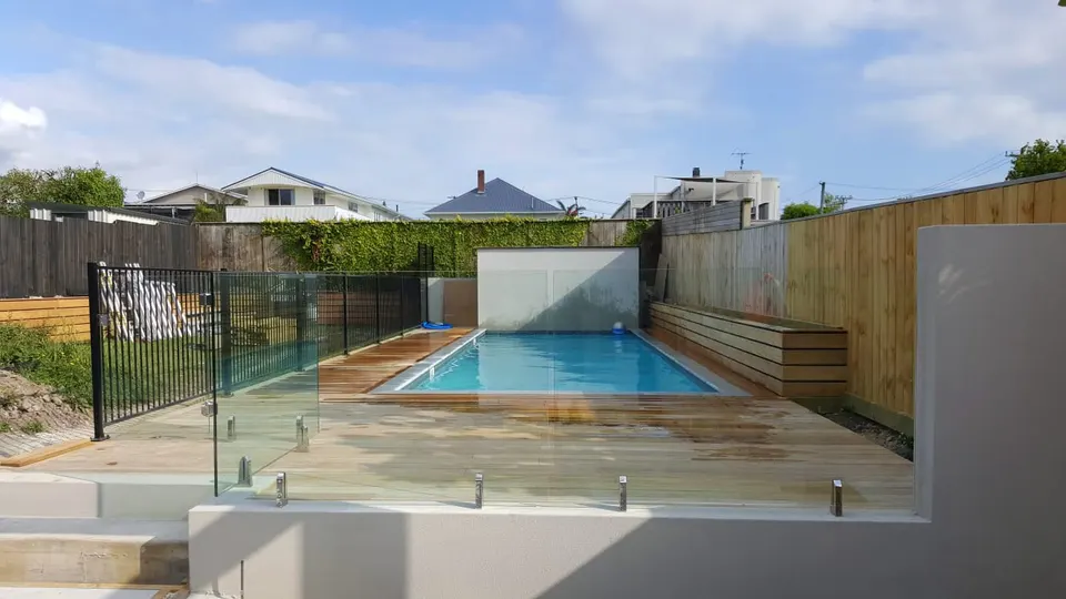 Glass pool fence with a black metal fence section around a courtyard pool