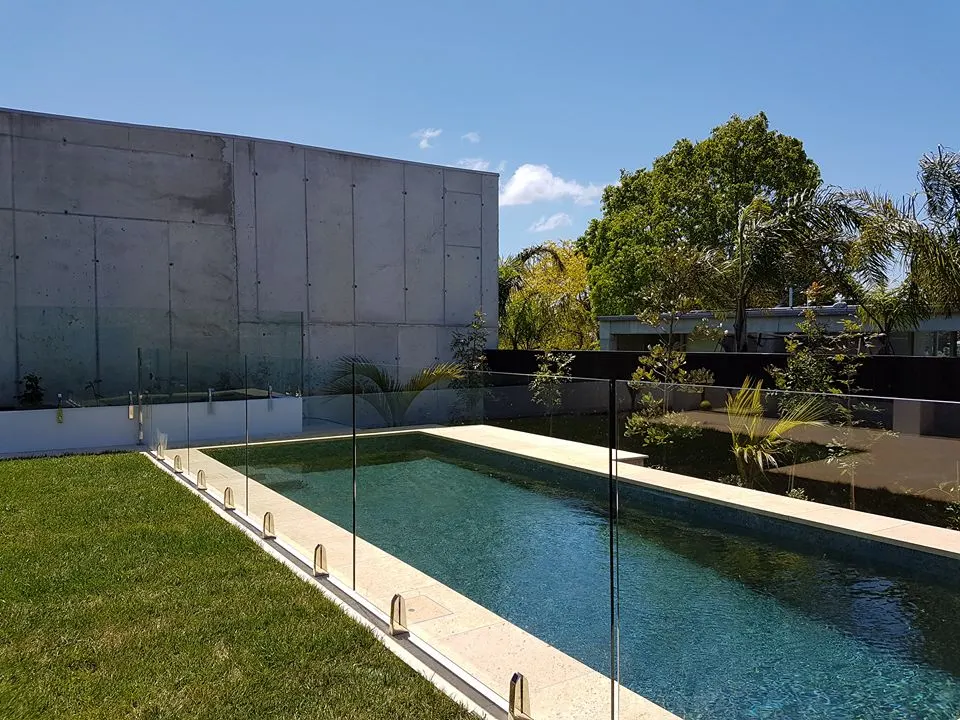 Glass pool fence along a long narrow pool beside a concrete wall