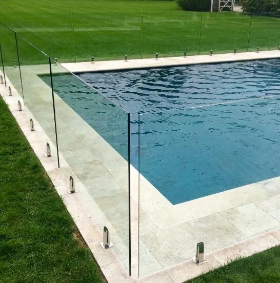 Glass pool fence at a pool corner with lawn and stone coping