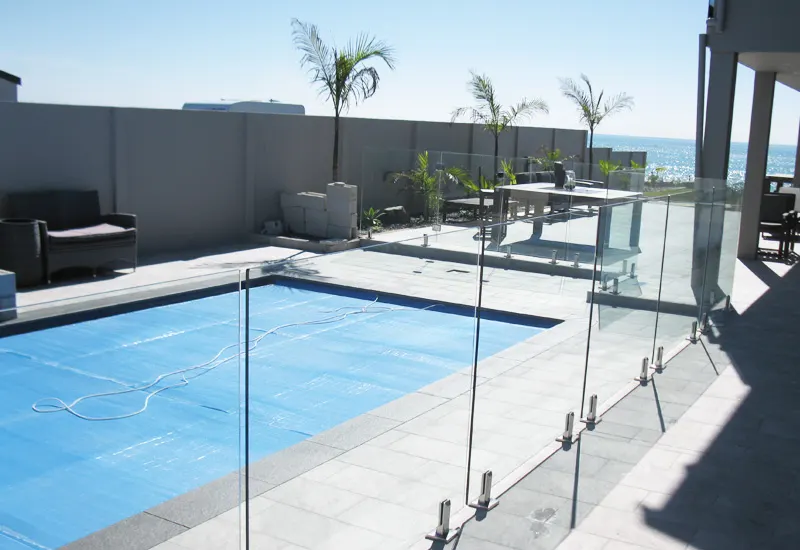 Glass pool fence around a covered pool in a courtyard